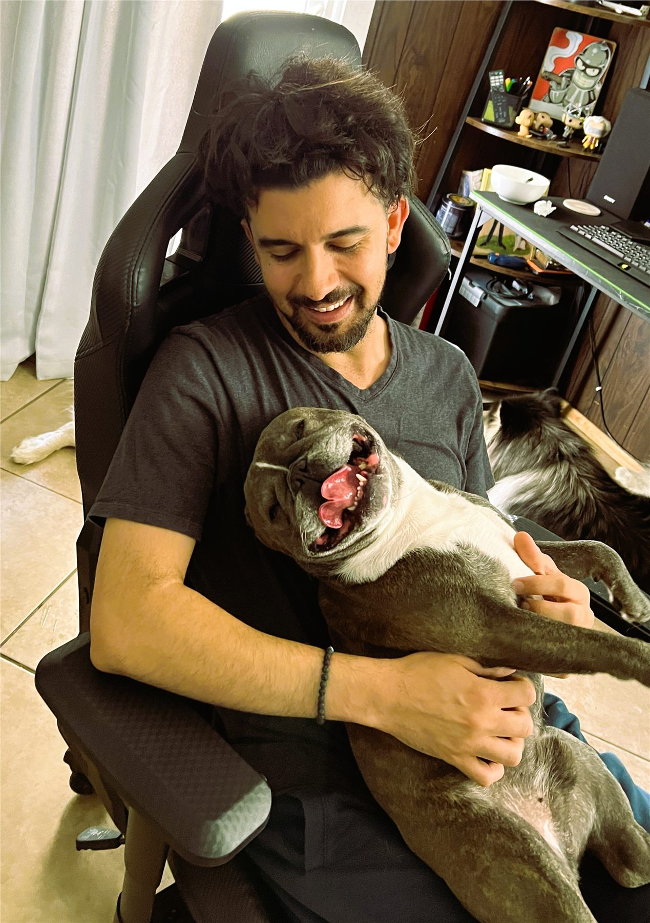 Ali smiling while cuddling a relaxed Frenchie